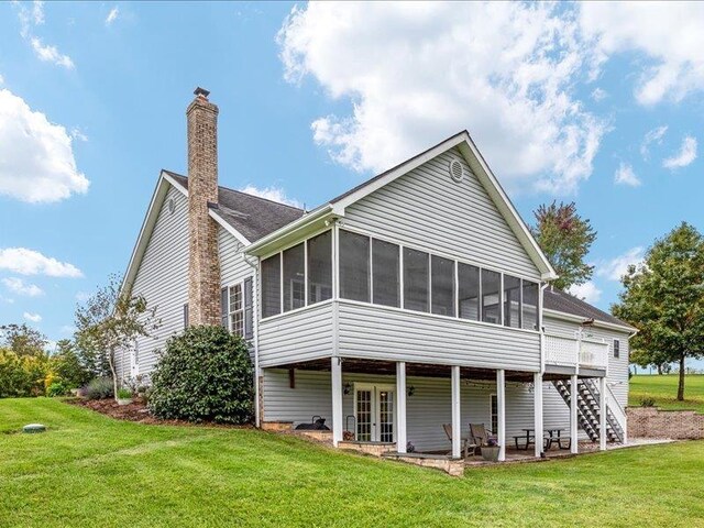 back of property with a sunroom, a yard, and a patio area