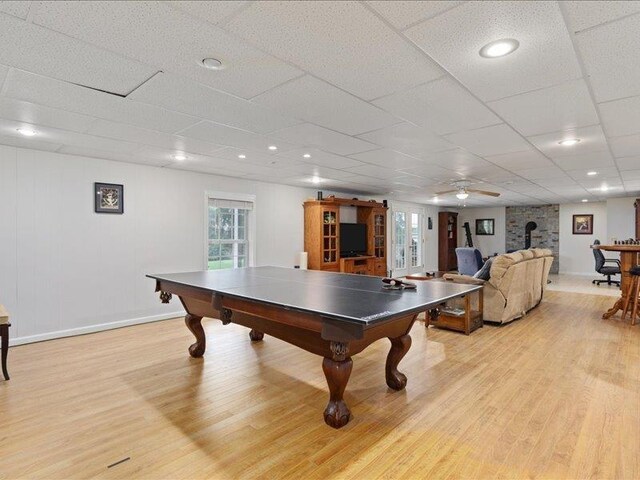 playroom featuring a wood stove, a paneled ceiling, and light hardwood / wood-style floors