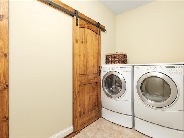 laundry area featuring light tile patterned flooring, washer and dryer, and a barn door