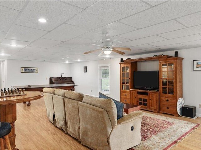 living room with a drop ceiling, light hardwood / wood-style flooring, and ceiling fan