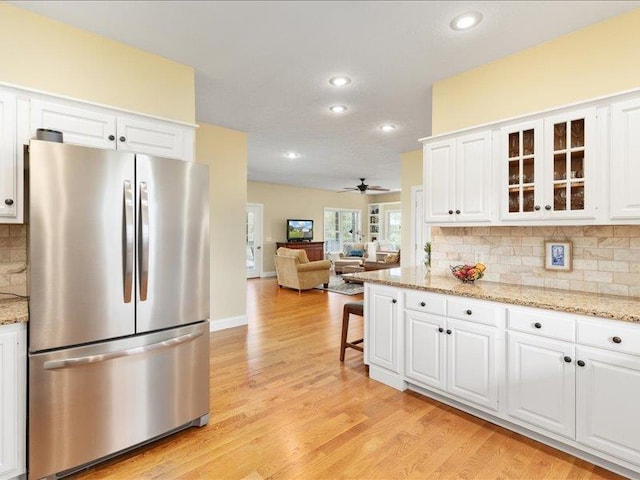 kitchen with white cabinetry, stainless steel fridge, light stone countertops, and light hardwood / wood-style floors