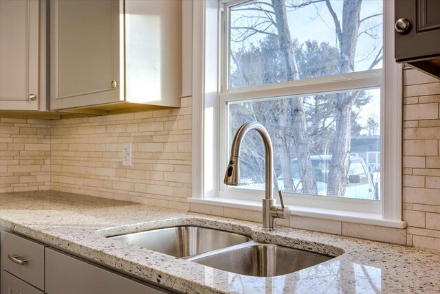 kitchen with sink, a wealth of natural light, and light stone countertops