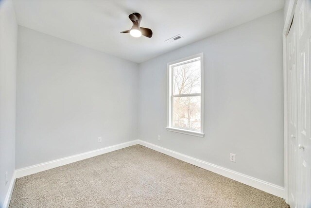 carpeted spare room with ceiling fan