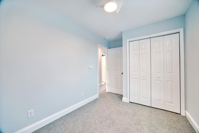 unfurnished bedroom with light colored carpet and a closet