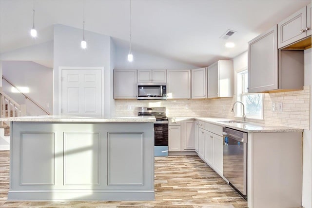 kitchen with appliances with stainless steel finishes, decorative light fixtures, sink, and a kitchen island