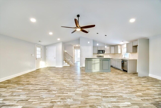 kitchen with vaulted ceiling, appliances with stainless steel finishes, light wood-type flooring, and gray cabinetry