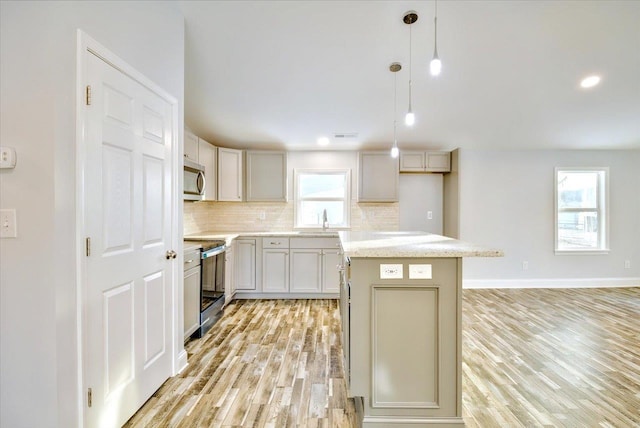 kitchen featuring pendant lighting, appliances with stainless steel finishes, a kitchen island, and backsplash