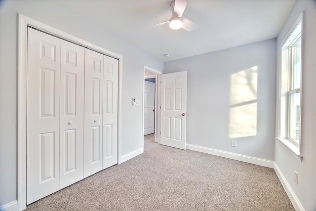 unfurnished bedroom with light carpet, ceiling fan, and a closet