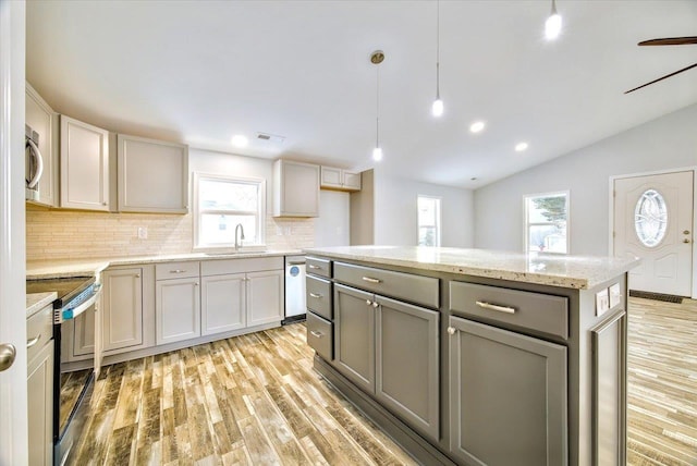 kitchen with sink, gray cabinetry, hanging light fixtures, stainless steel appliances, and light hardwood / wood-style floors