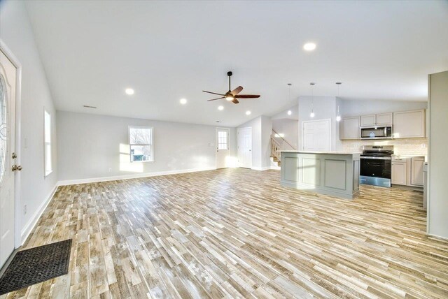 kitchen featuring gray cabinetry, decorative light fixtures, a center island, appliances with stainless steel finishes, and light hardwood / wood-style floors