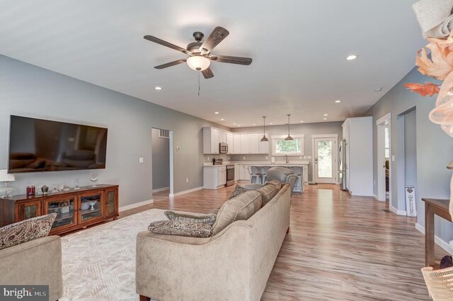 living room featuring light wood-style flooring, recessed lighting, baseboards, and ceiling fan