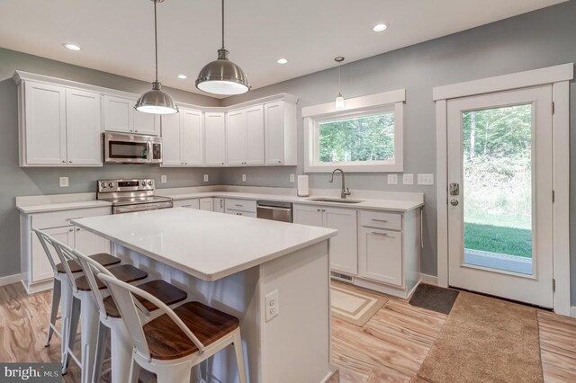 kitchen with a sink, stainless steel appliances, white cabinets, and light countertops