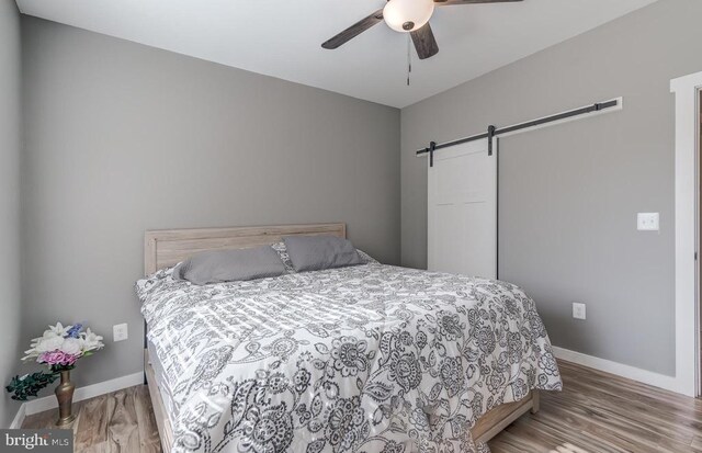 bedroom featuring a barn door, baseboards, and wood finished floors