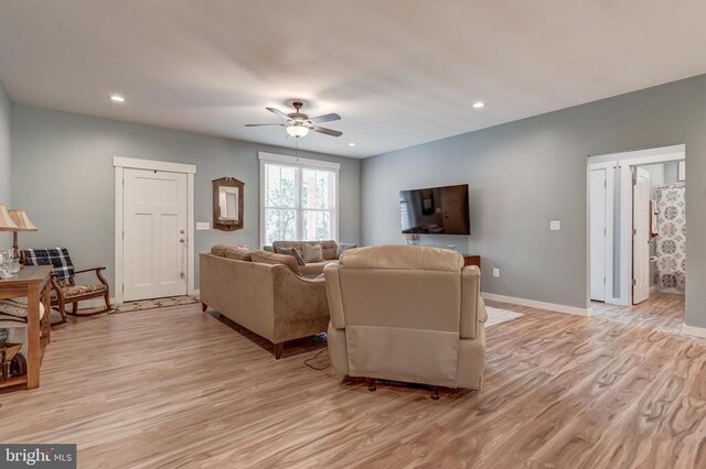 living room with light wood-style flooring, baseboards, and ceiling fan