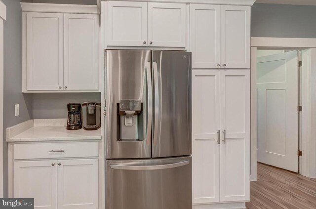 kitchen featuring white cabinets, stainless steel fridge with ice dispenser, and light wood finished floors