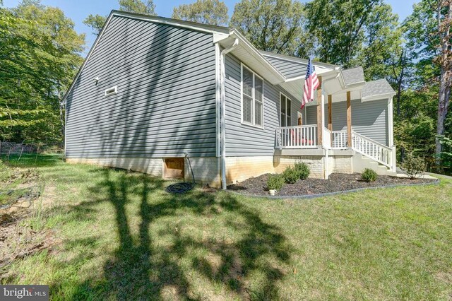 view of side of property featuring a lawn and a porch