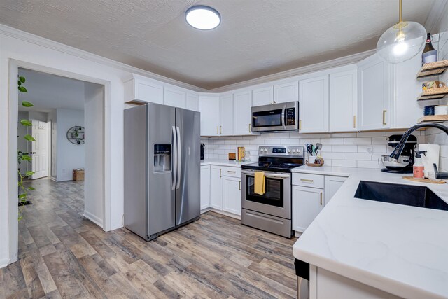 kitchen with pendant lighting, stainless steel appliances, and white cabinets