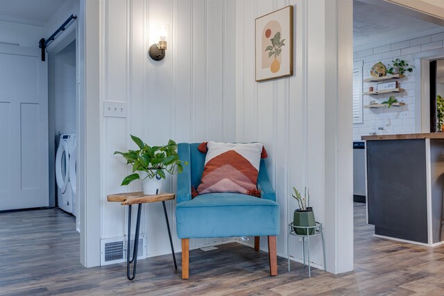 sitting room with washer / clothes dryer, a barn door, and hardwood / wood-style floors