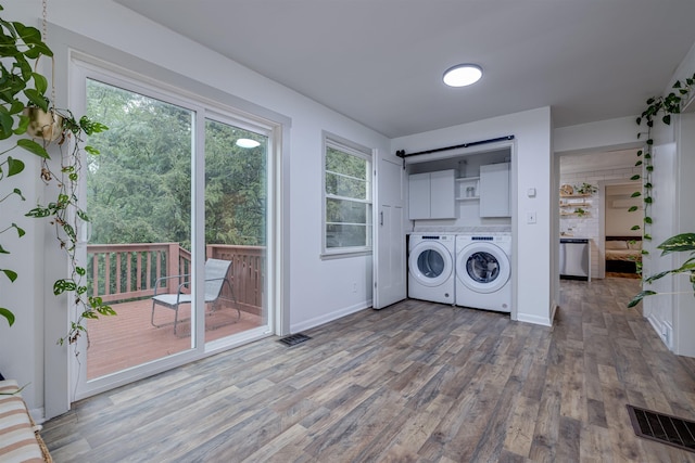 clothes washing area with hardwood / wood-style flooring, cabinets, and separate washer and dryer