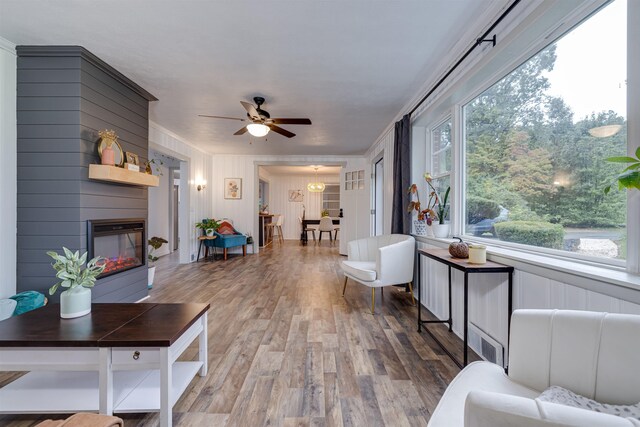 living room with wood-type flooring, a large fireplace, and ceiling fan