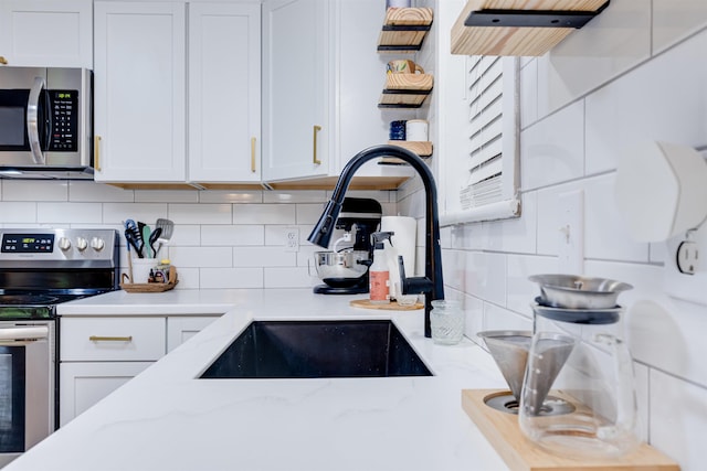 kitchen featuring white cabinetry, appliances with stainless steel finishes, sink, and backsplash