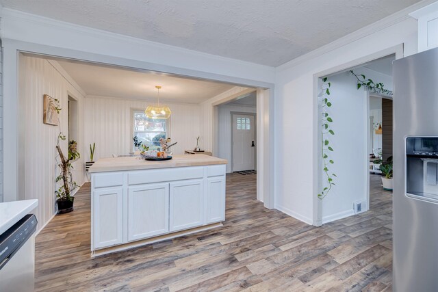 kitchen featuring pendant lighting, light hardwood / wood-style floors, white cabinets, and appliances with stainless steel finishes