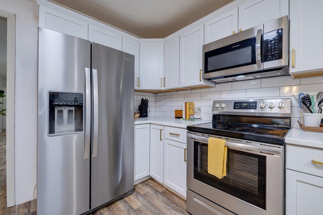 kitchen with white cabinetry, tasteful backsplash, light hardwood / wood-style floors, and appliances with stainless steel finishes