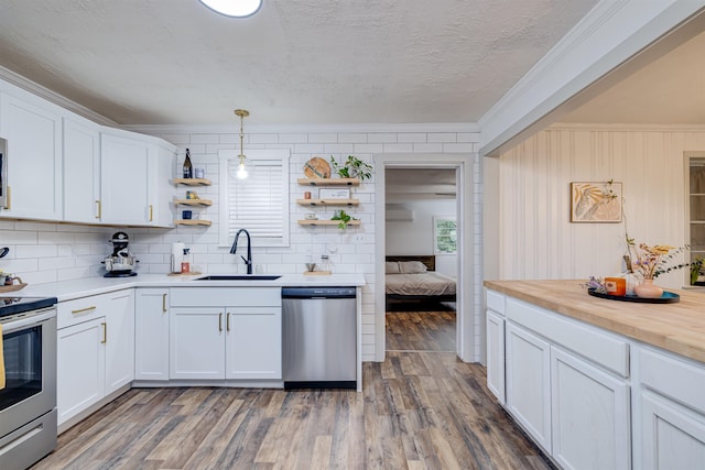 kitchen featuring stainless steel appliances, sink, pendant lighting, and white cabinets