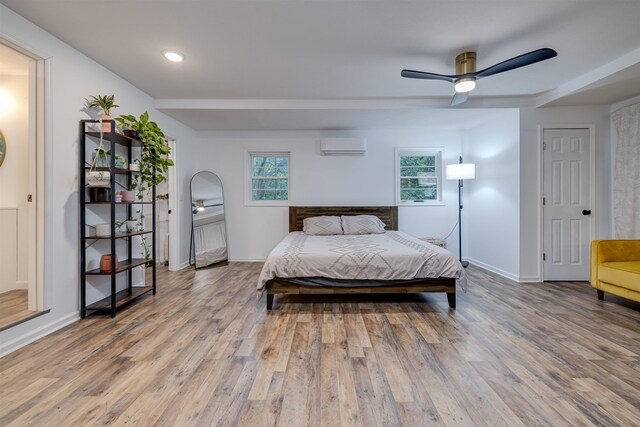 bedroom with ceiling fan, hardwood / wood-style floors, and a wall unit AC