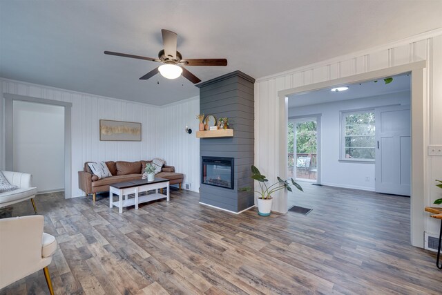 living room featuring hardwood / wood-style flooring, a multi sided fireplace, crown molding, and ceiling fan