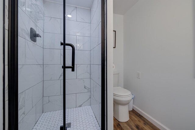 bathroom with hardwood / wood-style flooring, an enclosed shower, and toilet