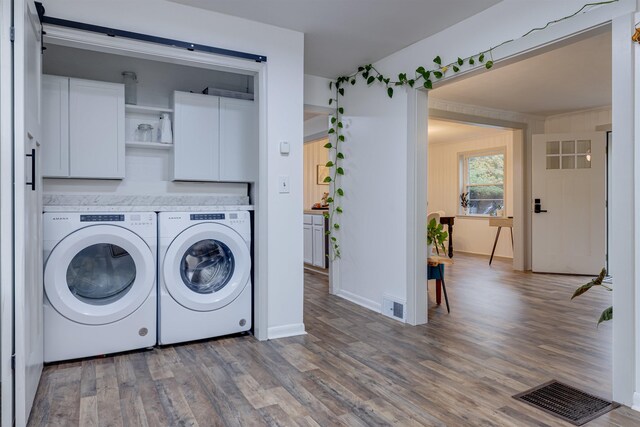 washroom with hardwood / wood-style floors, cabinets, and independent washer and dryer