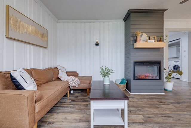 living room with washer / clothes dryer, a large fireplace, and dark hardwood / wood-style flooring