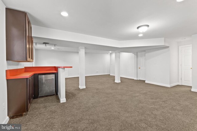 basement featuring indoor bar, dark colored carpet, and refrigerator