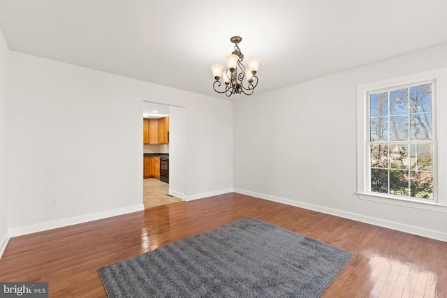 spare room featuring dark wood-type flooring and a chandelier