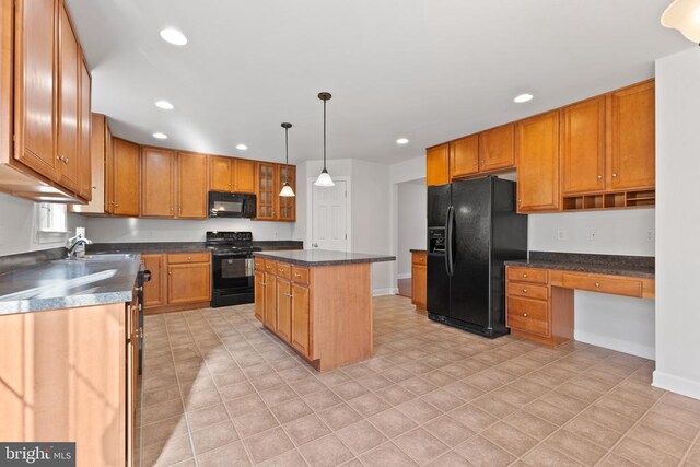 kitchen with sink, decorative light fixtures, built in desk, a kitchen island, and black appliances