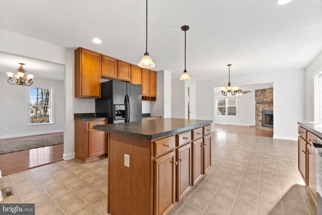 kitchen featuring an inviting chandelier, a fireplace, decorative light fixtures, and black fridge with ice dispenser