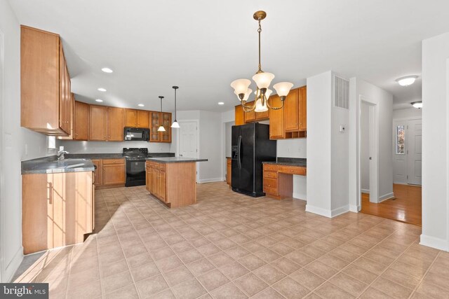 kitchen featuring an inviting chandelier, built in desk, hanging light fixtures, a kitchen island, and black appliances