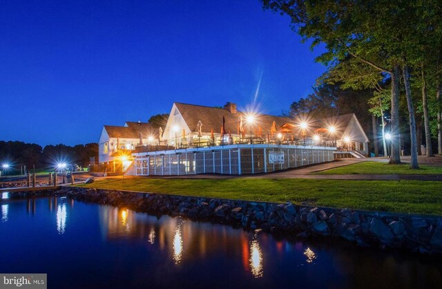 pool at twilight featuring a yard and a water view