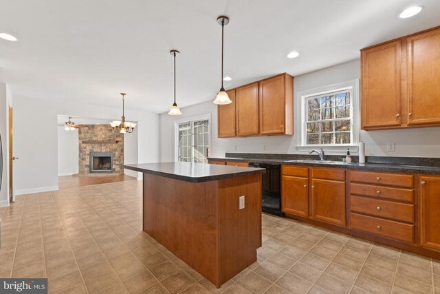 kitchen with dishwasher, a center island, a healthy amount of sunlight, a stone fireplace, and decorative light fixtures