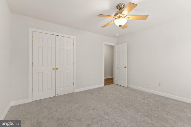 unfurnished bedroom featuring light carpet, a closet, and ceiling fan