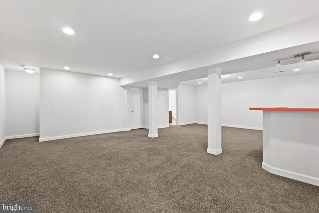 basement with dark colored carpet and bar area