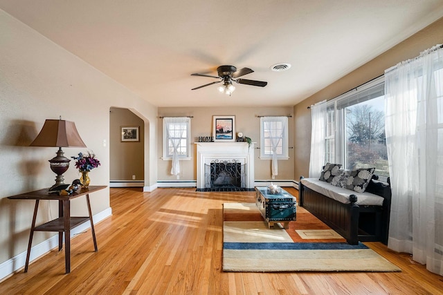 living room with light hardwood / wood-style flooring, ceiling fan, and baseboard heating