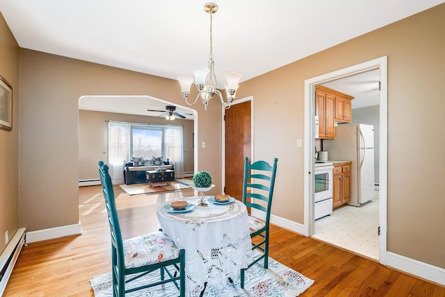 dining space with a baseboard radiator, ceiling fan with notable chandelier, and light hardwood / wood-style floors