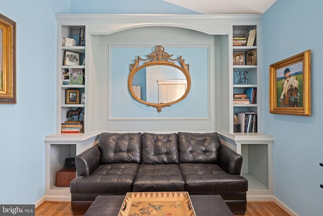 living room with built in shelves and hardwood / wood-style floors