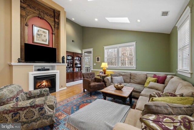 living room featuring wood-type flooring and lofted ceiling with skylight