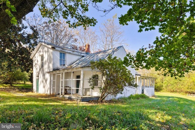 view of side of home featuring a sunroom and a lawn