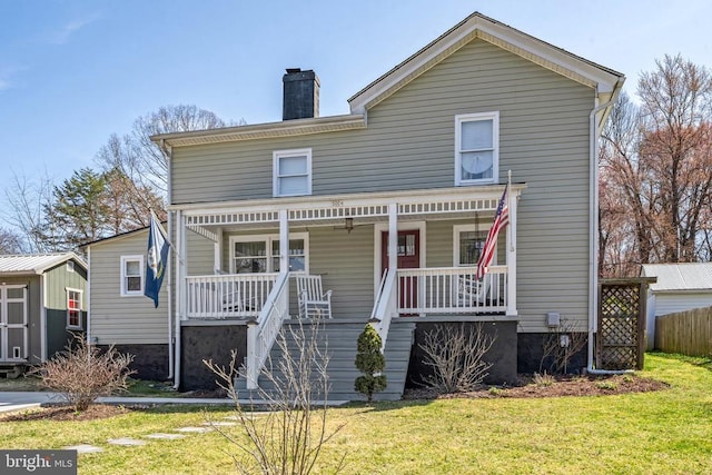 view of front facade featuring covered porch, a chimney, and a front yard