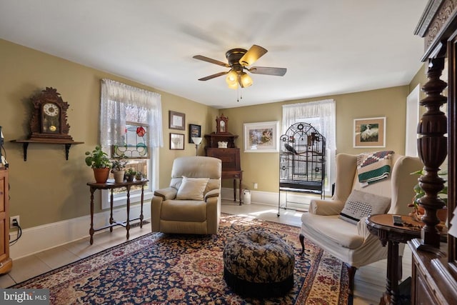 sitting room featuring tile patterned floors, baseboards, and a ceiling fan