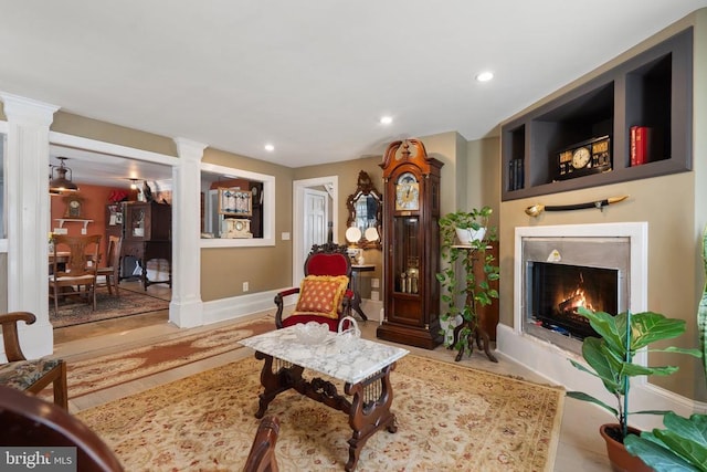 living area featuring recessed lighting, a fireplace, baseboards, and ornate columns